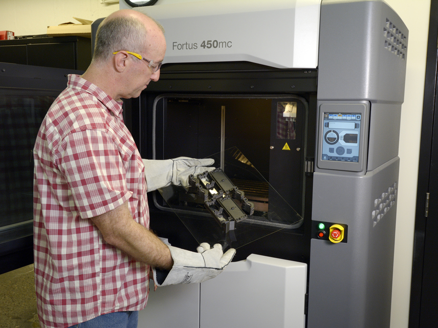 Man looking at part in 3D printer