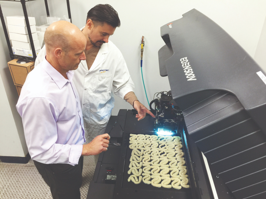 Two lab techs check the build tray.