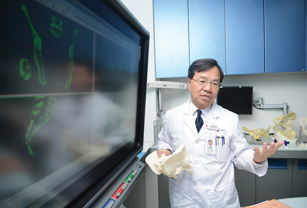 Doctor holding 3d printed bones near computer screen