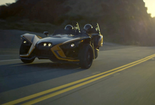 Two seat roadster driving down curvy road at dusk