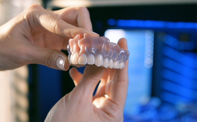 hands inspecting 3d printed dentures.jpg
